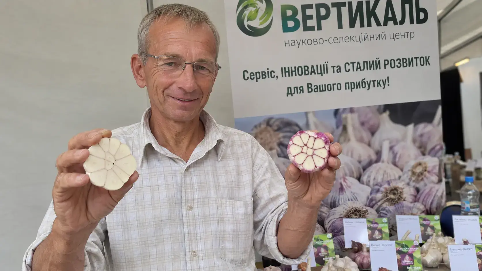 Фото: дослідна ділянка центру «Вертикаль» — рівні рядки часнику з пронумерованими табличками, селекціонер занотовує результати в польовий журнал.